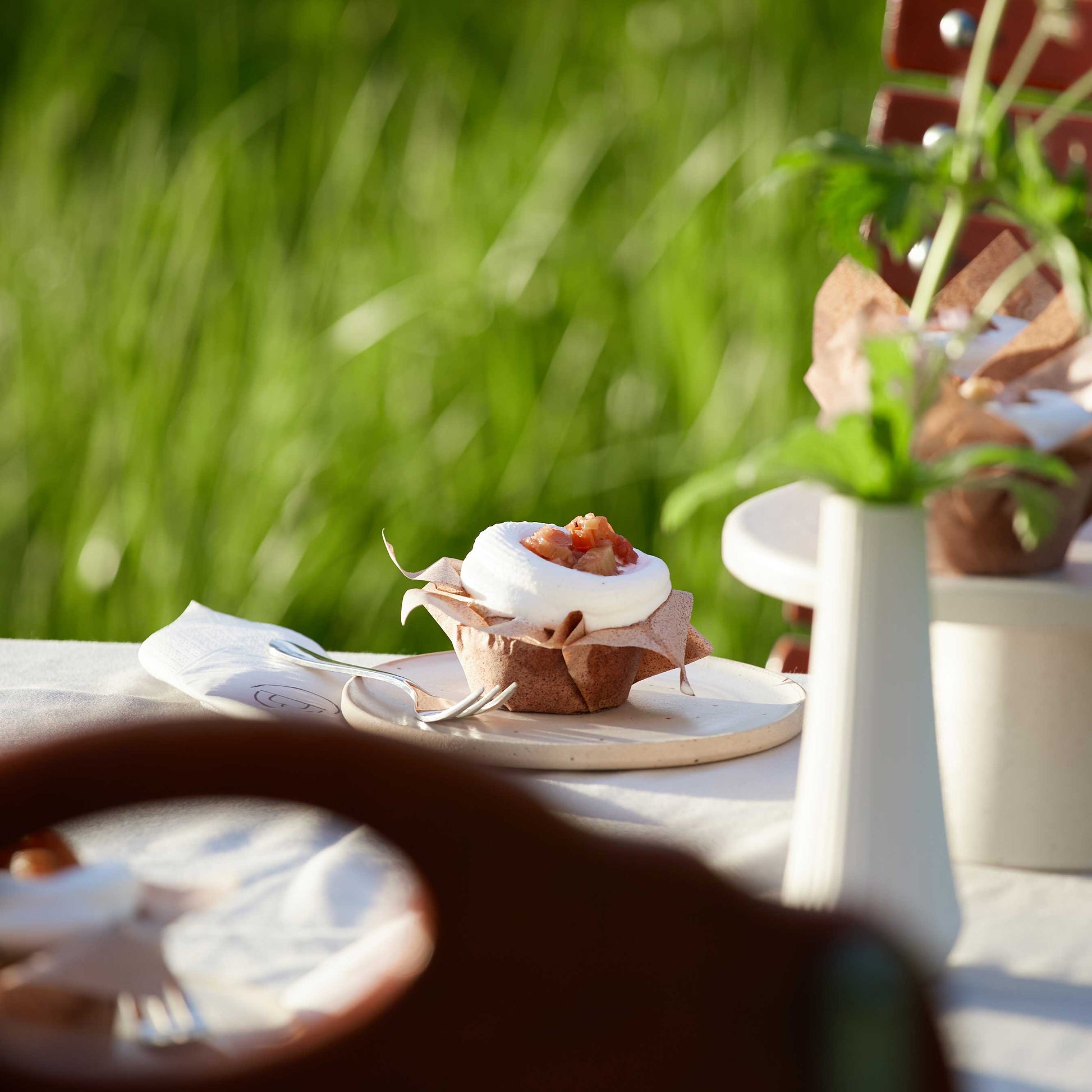 Rhabarber Cupcake mit Sahne auf einem gedeckten Tisch